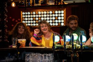 glad kvinde i fokus foran baren i rock'en på crazy daisy svendborg